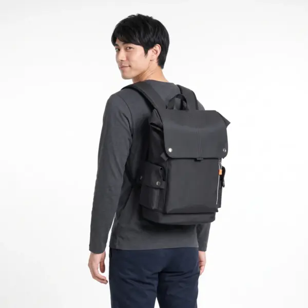 Black flap laptop backpack worn by a man, seen from behind