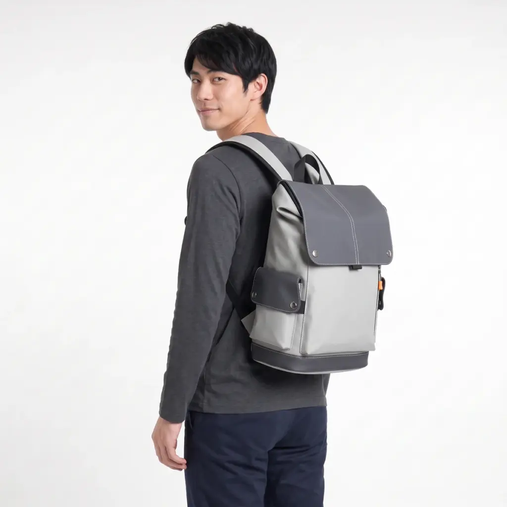Grey flap laptop backpack worn by a man, seen from behind
