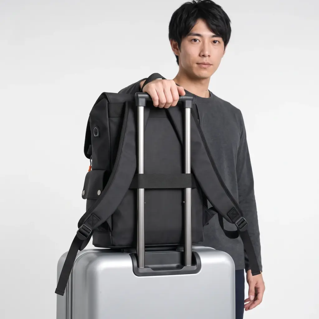 Flap laptop backpack slid over a suitcase handle with its trolley sleeve